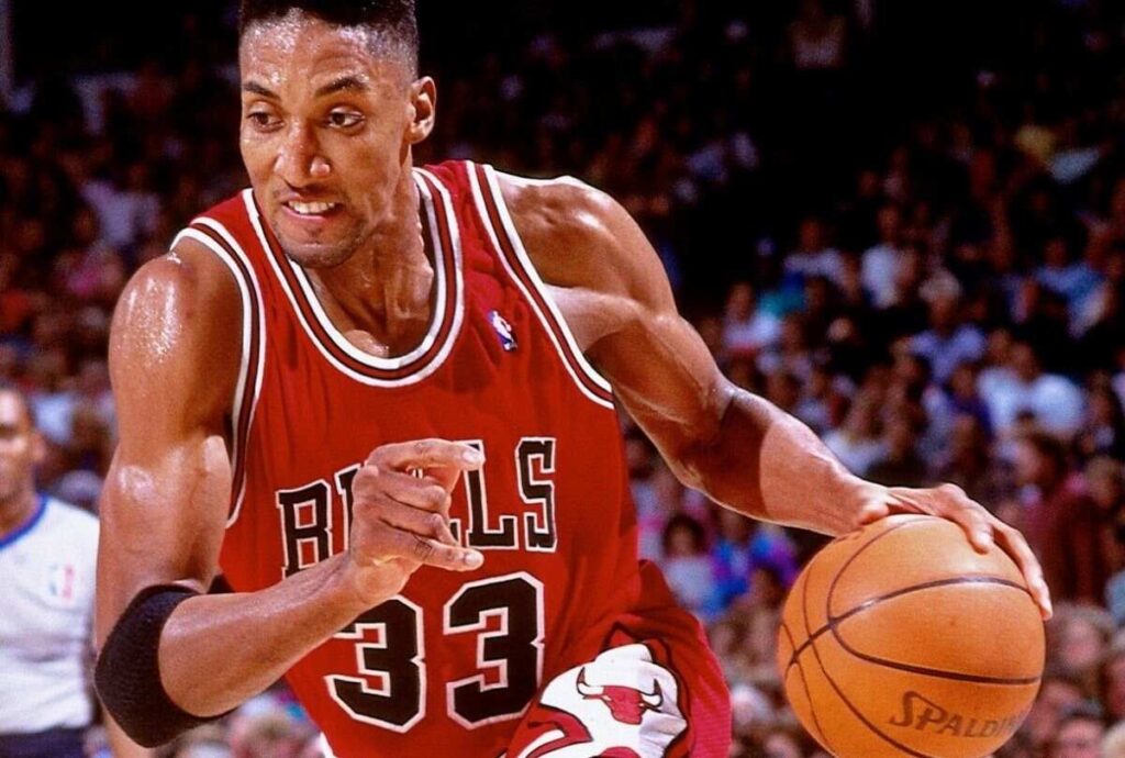 Scottie Pippen, in a red Chicago Bulls jersey, dribbling a basketball during a game.