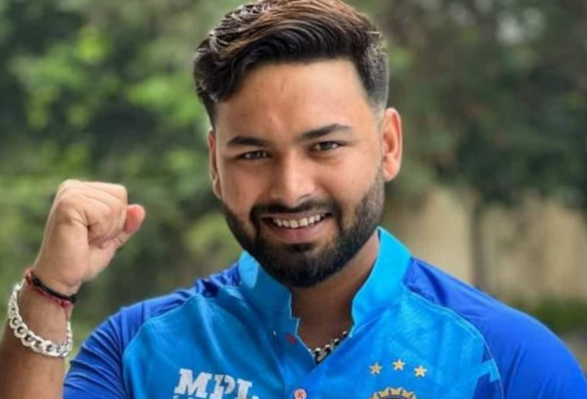 Rishabh Pant smiling and raising his fist, wearing a blue team jersey.